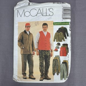 May include: A McCall's Sportsman sewing pattern envelope 9583 featuring illustrations of a jacket, vest, and pants. The front shows a person wearing a tan jacket and pants, and another wearing an orange vest, white shirt, and camouflage pants.