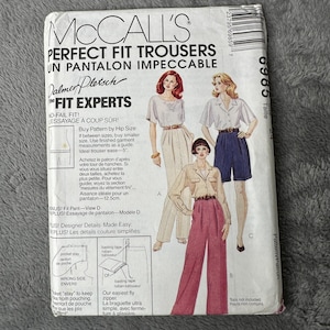 May include: A McCall's sewing pattern for Perfect Fit Trousers. The cover displays illustrations of women wearing different trouser designs. Text includes "Perfect Fit Trousers" and "Fit Experts". The pattern provides fitting guidance.