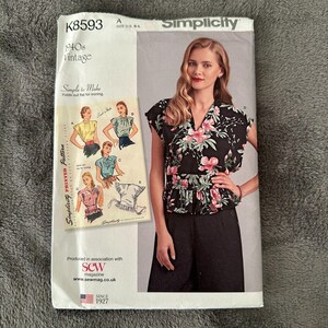 Puede incluir: Patrón de costura vintage Simplicity K8593 de los años 40. El patrón presenta a una mujer con un top negro floral con peplum y pantalones negros. El patrón incluye ilustraciones de diferentes estilos de top. Talla US B-L.