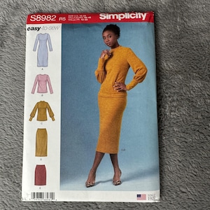 May include: Simplicity sewing pattern S8982 featuring a woman in a mustard-colored knit dress. The pattern includes illustrations of various dress styles. The cover has the text "easy-to-sew" and "SINCE 1927".