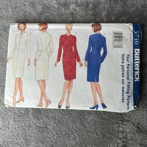 May include: A Butterick sewing pattern envelope featuring illustrations of four different dresses. The dresses are in cream, red, and blue. The envelope includes the text "Your Personal Fitting Pattern" and the number "5746".