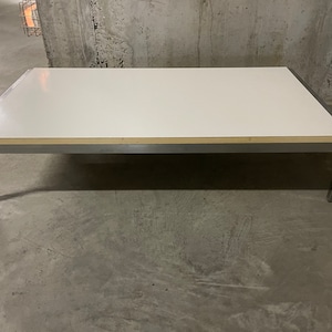 Peut inclure: Une table basse rectangulaire blanche avec un cadre en métal argenté. La table a un design simple et est faite de matériaux robustes.