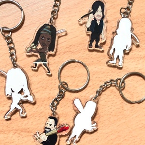 Può includere: Sei portachiavi in ​​acrilico trasparente con personaggi dei cartoni animati della serie TV The Walking Dead. I personaggi includono Daryl Dixon, Michonne, Negan e tre personaggi vuoti. Ogni portachiavi ha un anello di metallo argentato.