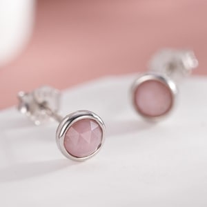 Può includere: Un paio di orecchini a bottone in argento con accenti di pietre preziose rosa.