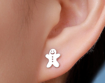 May include: A close-up of a person's ear wearing a silver gingerbread man stud earring.