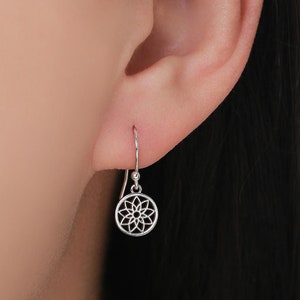 Könnte beinhalten: Silberne Ohrhänger mit einem zarten runden Design, das ein Mandala-Muster zeigt.