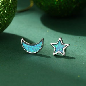 May include: A pair of silver earrings with blue opal stones. One earring is a crescent moon shape and the other is a star shape.