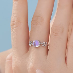 Peut inclure: Une bague en argent avec une pierre irisée violette et un motif de feuilles.