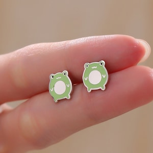 May include: A pair of silver frog stud earrings with green enamel and white accents.