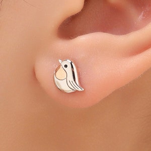 May include: Silver stud earrings featuring a small, detailed robin design with a yellow breast.