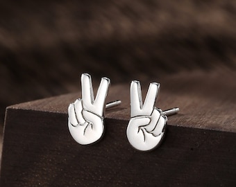 May include: A pair of silver peace sign earrings. The earrings are small and delicate, and they are perfect for adding a touch of peace and love to any outfit.