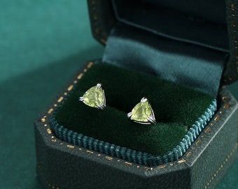 May include: A pair of green gemstone earrings in a green velvet jewelry box. The earrings are triangular shaped and set in silver.