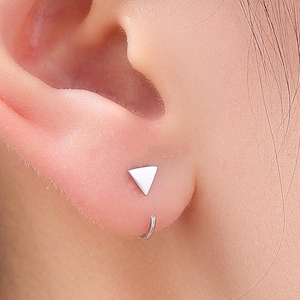 May include: A pair of silver triangle earrings. The earrings are small and simple, and they are perfect for everyday wear.