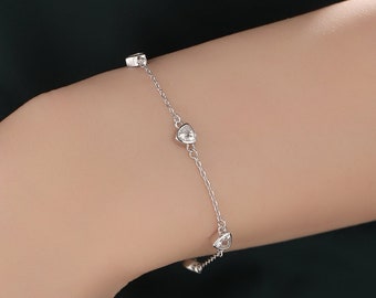 May include: A silver chain bracelet with small clear stones. The bracelet is on a person's wrist.
