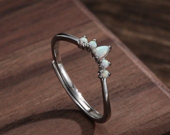 May include: A silver ring with a row of white opal stones set in a curved design.
