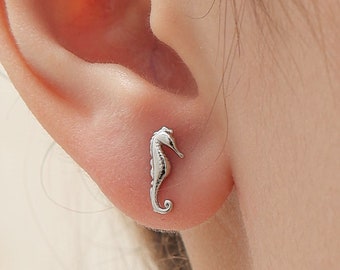 May include: Silver stud earrings featuring a small, detailed seahorse design.