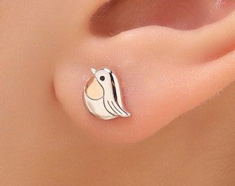 Könnte beinhalten: Silberne Ohrstecker mit einem kleinen, detaillierten Rotkehlchen-Design mit gelber Brust.