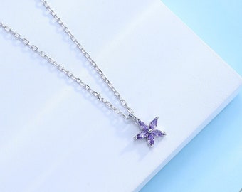 May include: A silver chain necklace with a small purple flower pendant.