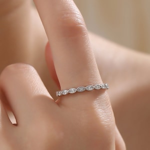 May include: A silver band ring with a row of small, clear, marquise-shaped stones.