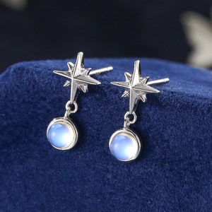 May include: A pair of silver earrings with a star design and a round, iridescent moonstone pendant.