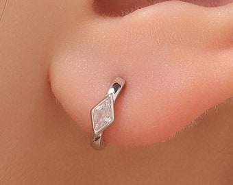 May include: A silver hoop earring with a small, clear diamond-shaped gemstone.