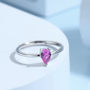May include: A silver ring with a teardrop-shaped pink gemstone.