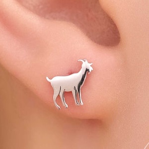 May include: Silver goat stud earrings. The earrings are small and delicate, and the goat is facing to the right.