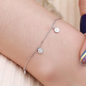 Puede incluir: Un brazalete de cadena de plata con dos peque&ntilde;os dijes redondos de plata texturizados.