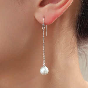May include: Silver dangle earrings with a single white pearl at the end of the chain.