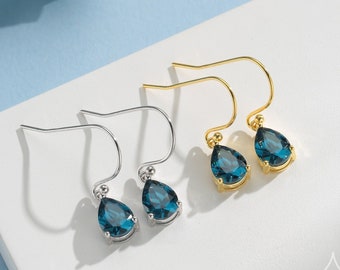 May include: A pair of teardrop-shaped earrings with blue gemstones. One pair has silver hooks and the other has gold hooks.