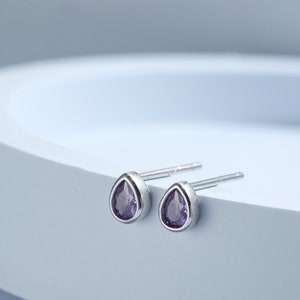 Puede incluir: Un par de pendientes de plata en forma de lágrima con piedras preciosas púrpuras.