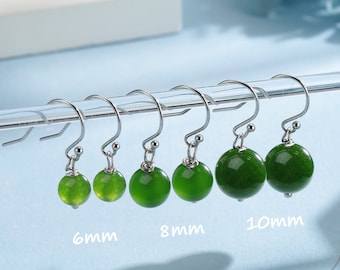 May include: Five pairs of green jade stone earrings with silver hooks. The earrings are displayed on a white stand and are labeled with their size in millimeters: 6mm, 8mm, and 10mm.