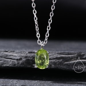May include: A silver chain necklace with a green oval peridot pendant.