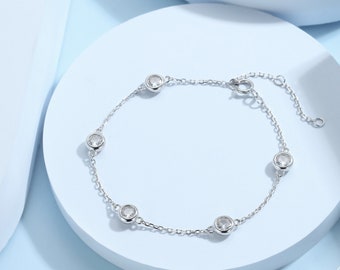 May include: A silver chain bracelet with five clear round stones. The bracelet has a lobster clasp closure.