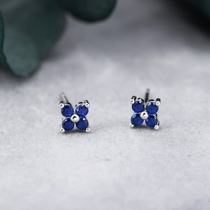 Puede incluir: Un par de pendientes de botón de plata con un diseño de trébol de cuatro hojas. Cada trébol tiene cinco piedras preciosas azules.