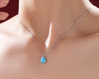 May include: A silver chain necklace with a teardrop-shaped turquoise pendant.