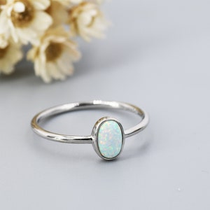 Könnte beinhalten: Ein zarter Silberring mit einem weißen Opal-Edelstein. Der Ring ist schlicht und elegant, perfekt für den Alltag.