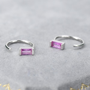 May include: A pair of silver hoop earrings with a pink rectangular gemstone set in each hoop.