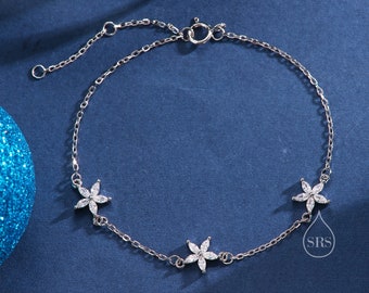 May include: A silver chain bracelet with three flower-shaped charms, each adorned with clear cubic zirconia stones. The bracelet has an adjustable clasp.