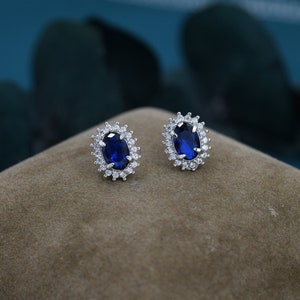 May include: A pair of silver earrings with a blue oval gemstone surrounded by smaller clear gemstones.