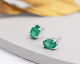 Puede incluir: Un par de pendientes de plata con piedras preciosas verdes de forma ovalada.