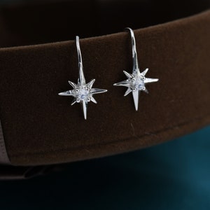 May include: A pair of silver star-shaped earrings with a clear crystal in the centre of each star.