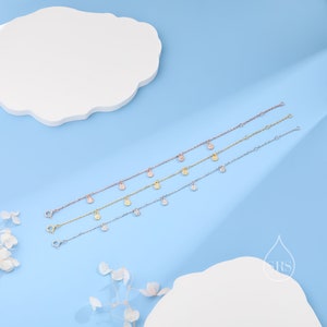 Puede incluir: Cuatro delicados brazaletes de oro, plata y oro rosa con peque&ntilde;os colgantes redondos engastados con pav&eacute;. Los colgantes cuelgan de la cadena y est&aacute;n espaciados uniformemente.