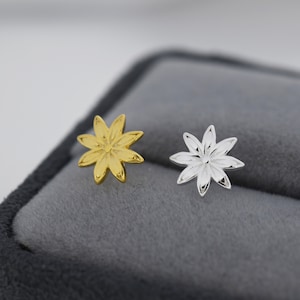 May include: A pair of flower-shaped earrings, one gold and one silver. The earrings are small and delicate, with a simple design.