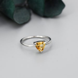May include: A silver ring featuring a triangular, yellow citrine gemstone.