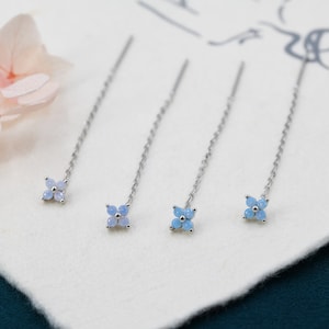 Puede incluir: Cuatro horquillas de plata con detalles de flores de ópalo azul. Cada horquilla tiene una cadena delicada y un pequeño grupo de cuatro piedras de ópalo.