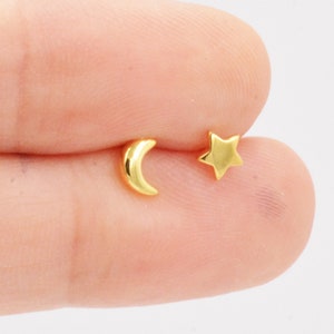 May include: A pair of gold earrings featuring a crescent moon and a five-pointed star.