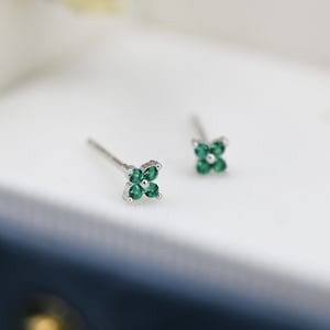 May include: A pair of silver stud earrings with a four-leaf clover design featuring green gemstones.