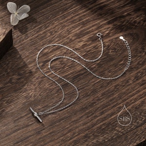 May include: A silver chain necklace with a toggle clasp. The chain is made of small, round links. The toggle clasp is a simple bar with a round ball on each end.