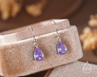 May include: A pair of silver dangle earrings with pear-shaped purple gemstones.